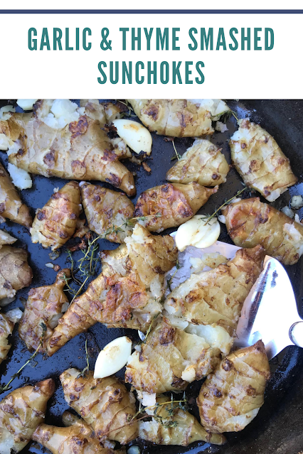 Finished skillet of smashed sunchokes with a spatula.