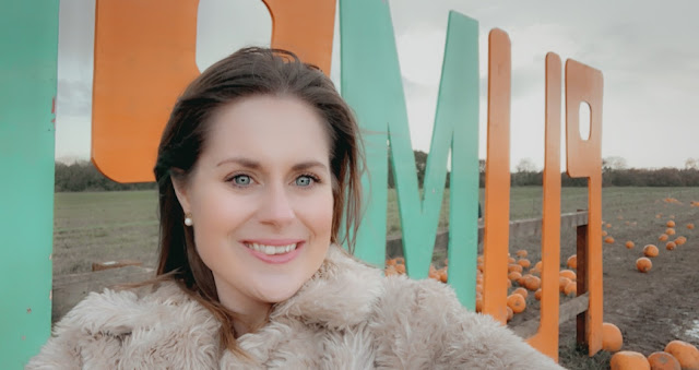 Woman smiling in front of Pumpkins sign