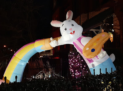 Large inflatable arch made up of a rainbow and an Easter bunny. Lit up at night.