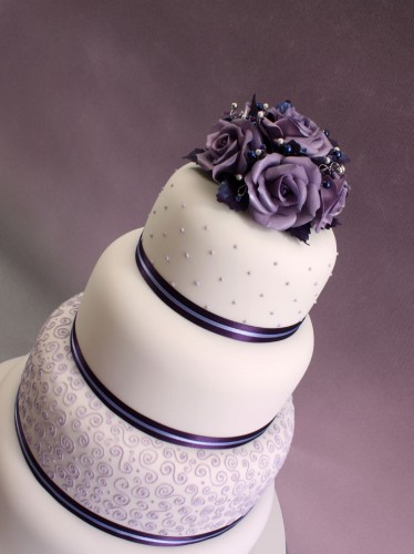 4 tier round cake with ribbons around every tier swirls on second tier and