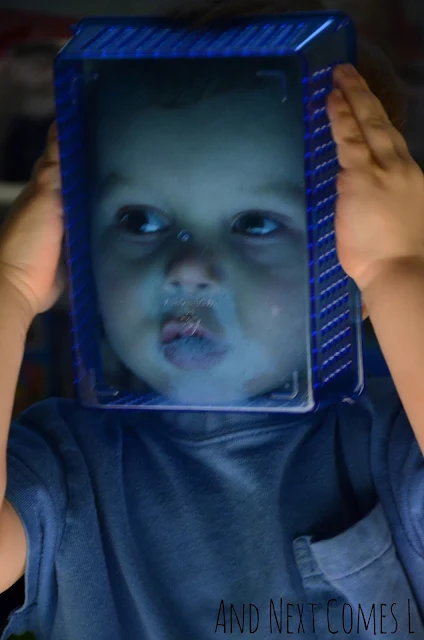 A toddler holding up a plastic container to his face