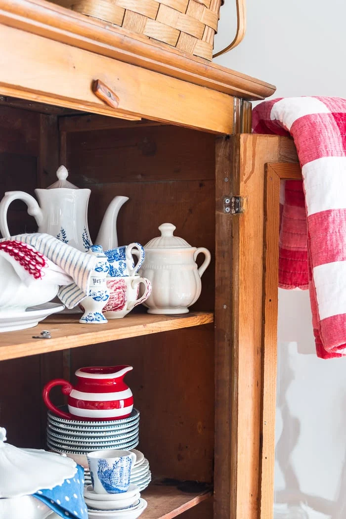 red and white checked quilt hanging over open hutch door