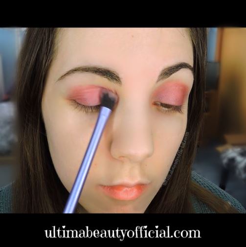 Ultima Beauty's face: sweeping purple eyeshadow on eye lid with an eyeshadow brush.