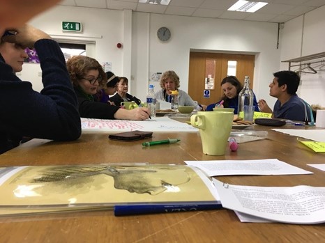 The Brain Charity research team sat around a table analysing Antonia's story and portraits. Some people are talking and some are writing.