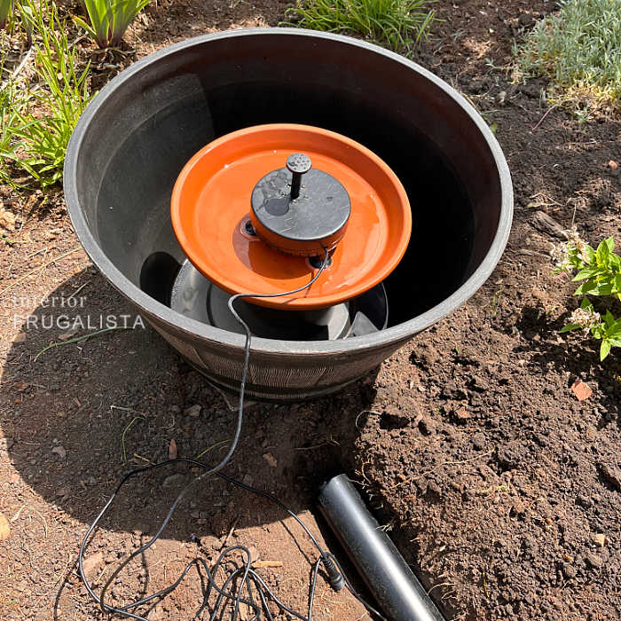 Set a flower pot saucer on top of a piece of PVC pipe inside a barrel planter for rechargeable solar water fountain pump.