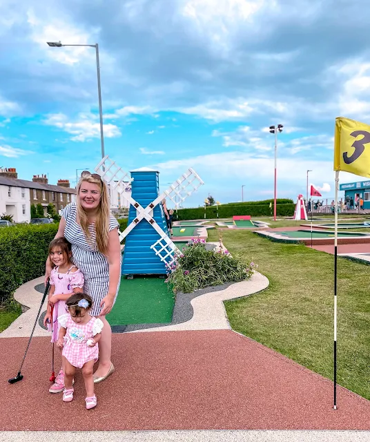 A mum and 2 children with golf clubs on the Arnold Palmer mini golf course in Southend