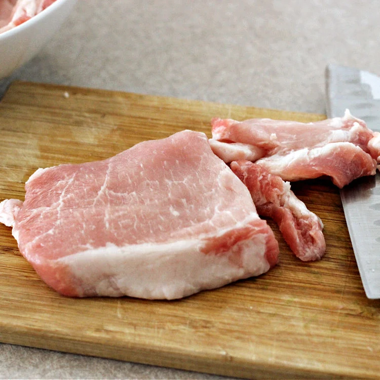 Pork chop being cut in thin strips for quick and easy pork and cabbage stir fry bowls