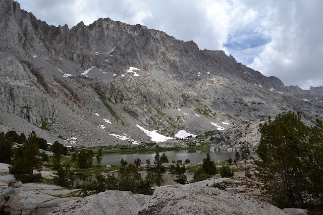 grey rocks dropping to green flats around ponds