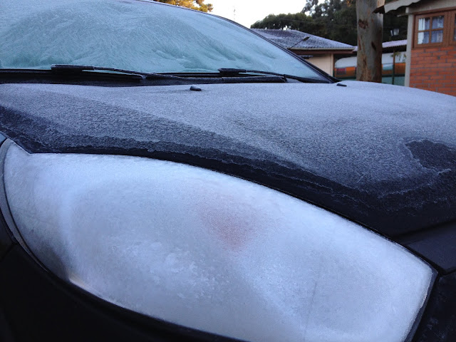 Parte da frente do carro coberta com uma crosta de gelo da geada.