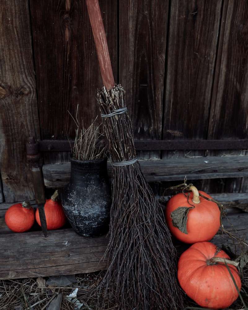 a witch's broom and pumpkins against a door