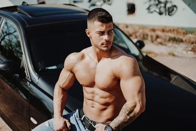 A bodybuilder sit on a car