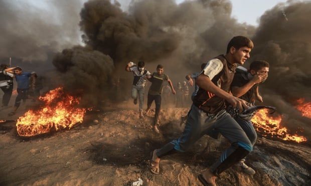 Palestinian protesters run to take cover from teargas fired by Israeli troops during clashes on the Gaza-Israel border.