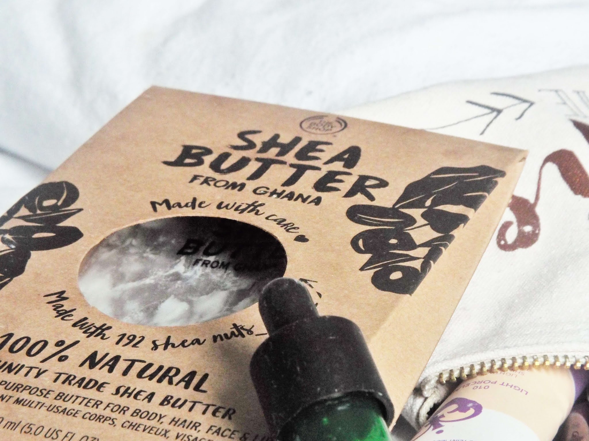 The Body Shop 100% Natural Community Trade Shea Butter, in a clear plastic pouch, encased in thin, brown card box, with hints to beauty recipes you can make with the product on the back..