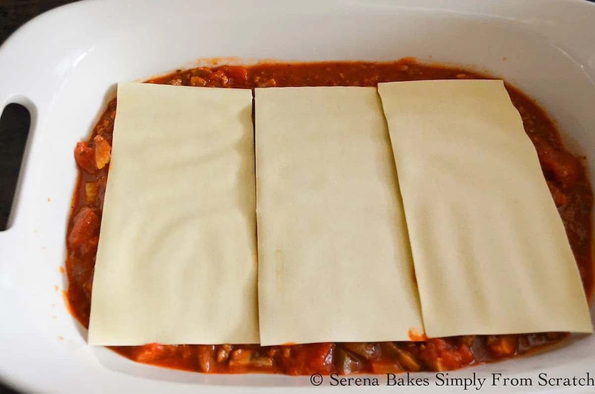 Lasagna Noodle Sheets layered on top of meat sauce in a pan for Easy Homemade Lasagna.