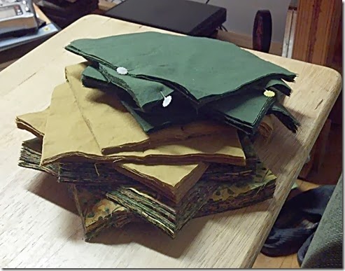 Various stacks of quilt squares, with at least one stack containing 24 layers of fabric.
