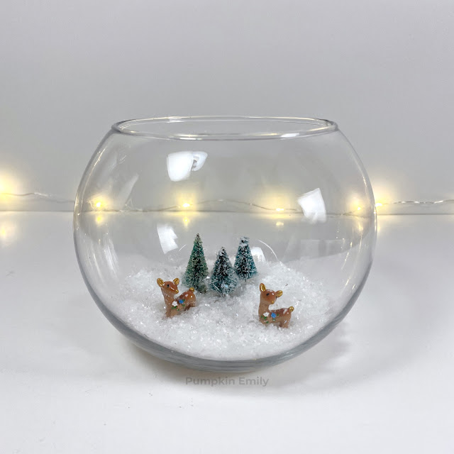 A winter wonderland bowl terrarium with snow, mini deer, and trees.