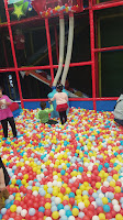 Picture of two kids feeding colourful balls through tubes in a Blippi style ball pit playground.