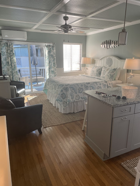 A view of the room. Kitchen is on the right, bed is in front of that, two chairs and a tv stand are to the left of the bed.