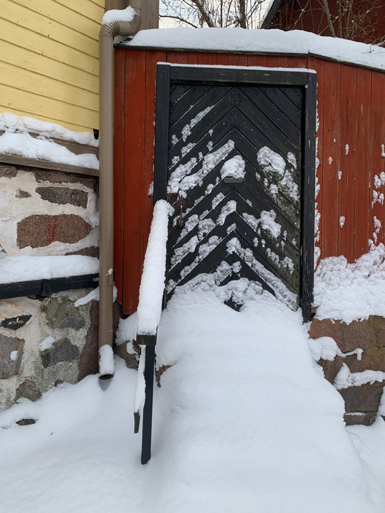 A lot of snow in front of a black door