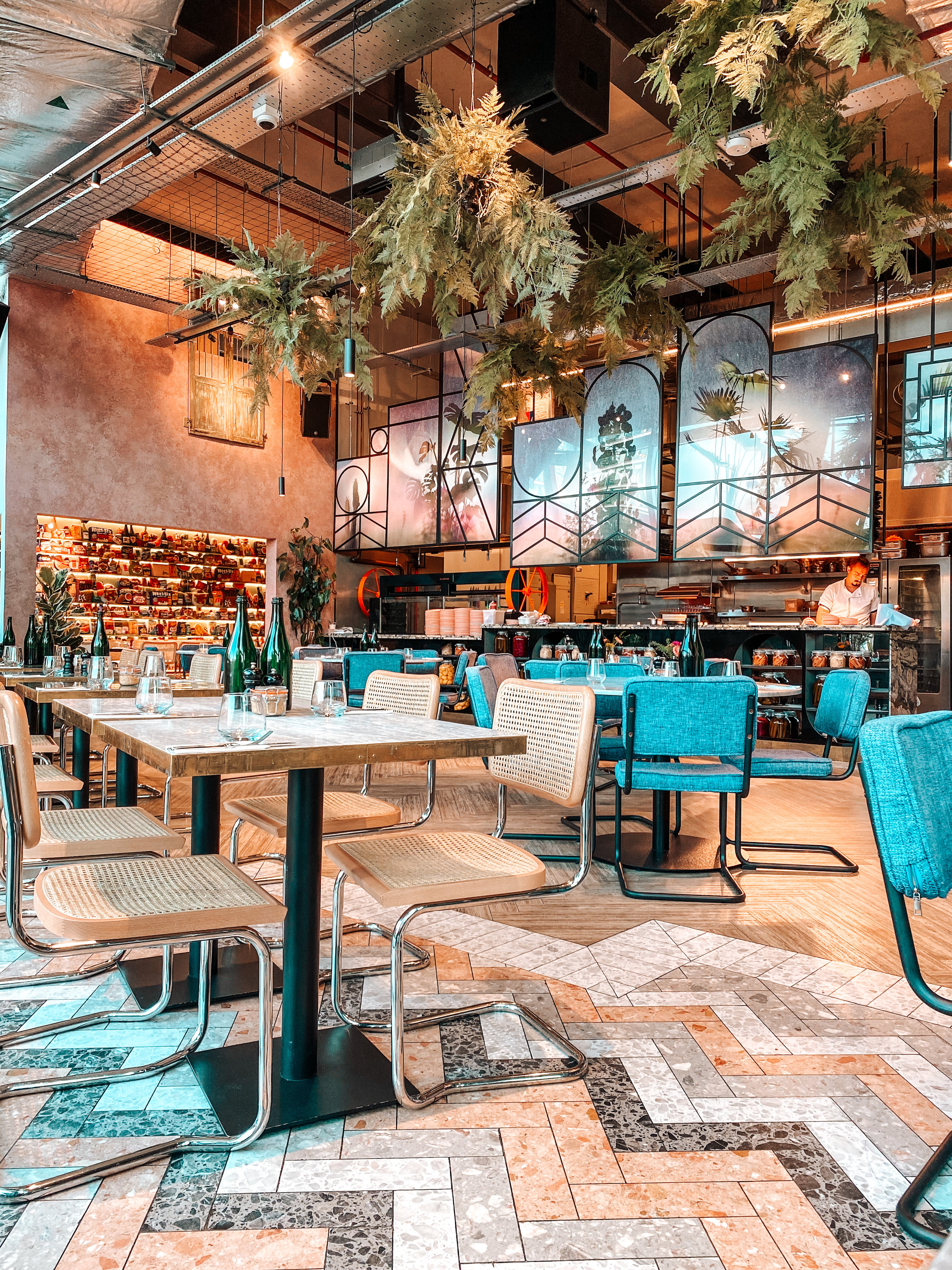 salle du restaurant brunch bondi green avec sièges cannages et bleus en velour et le bar en arrière plan avec un serveur