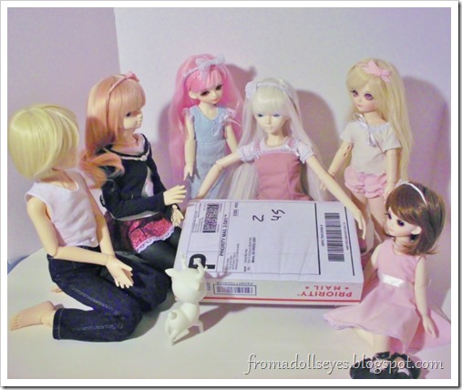 A group of several ball jointed dolls gathered around a package that came in the mail.  They are getting ready to open it.