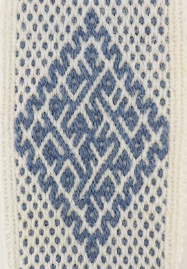 A photo of a blue and white tablet woven band patterned with blue diagonal lines and dots on a white background. The blue lines form a broken spiralling motif inside a zig-zag lozenge.
