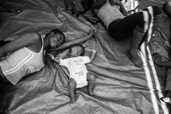 Photo: African migrant  mother and her child on the  deck of a ship after being  rescued at sea