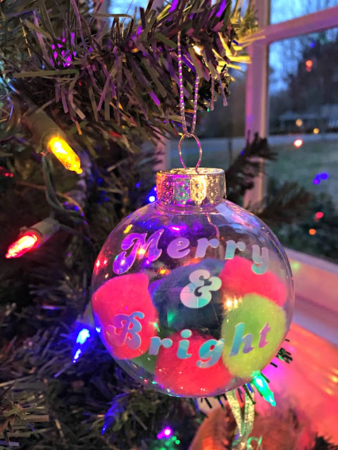 I used plastic ball ornaments, bright pom poms, and holographic vinyl to make this Festive Pom Pom Filled Christmas Ornament.
