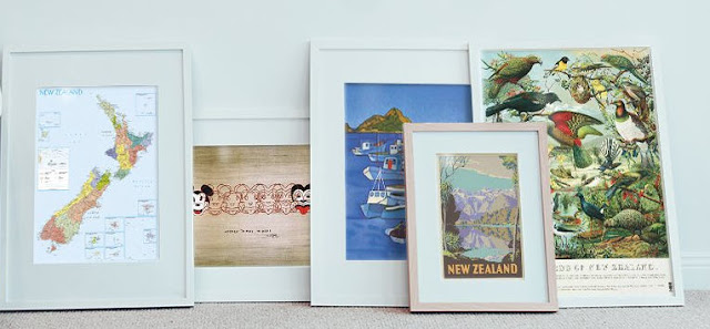 A row of framed New Zealand art prints leaning against a wall