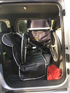 close up with the sliding side-door open, and a manual wheelchair (white framed quickie helium) placed on the back seat.