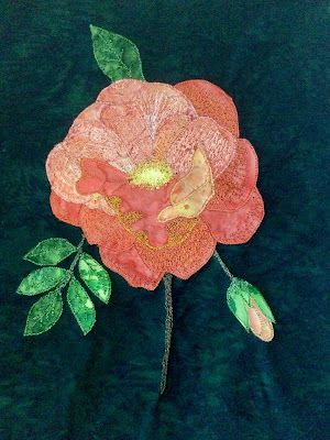 A fabric applique of an orange rose on a green background