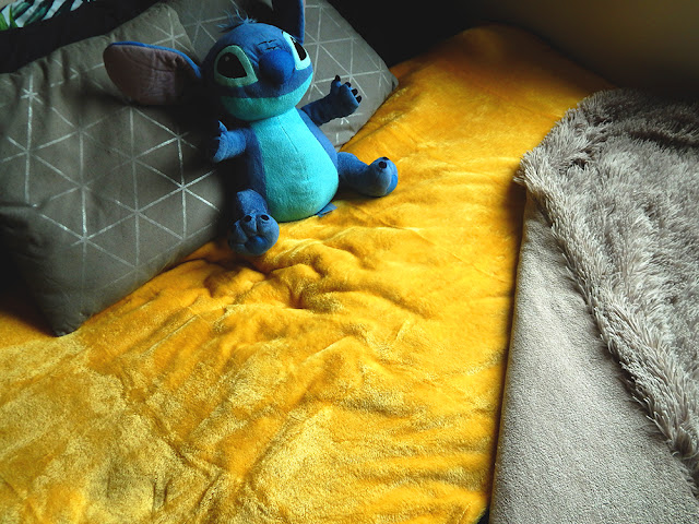 A yellow throw blanket tucked into a gray shaggy blanket