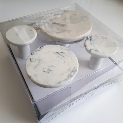 Four large marble-look round wall hooks of varying sizes in packaging