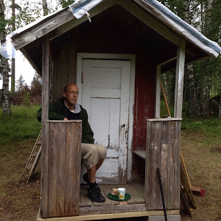 Hasse i grön fleecetröja sitter på verandabänken. Hans långa ben får knappt plats. På golvet står en liten grön bricka med kaffekopp och fikabröd.