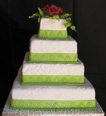 Elegant multitiered white square wedding cake with green ribbon trimming