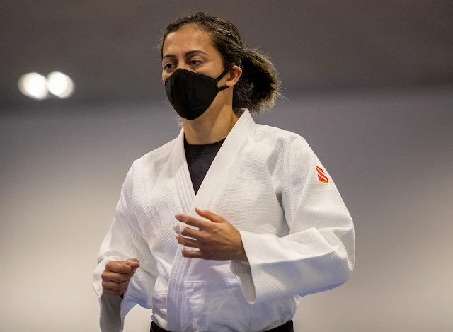 Lúcia Araújo usando um judogui branco e com uma máscara preta no rosto