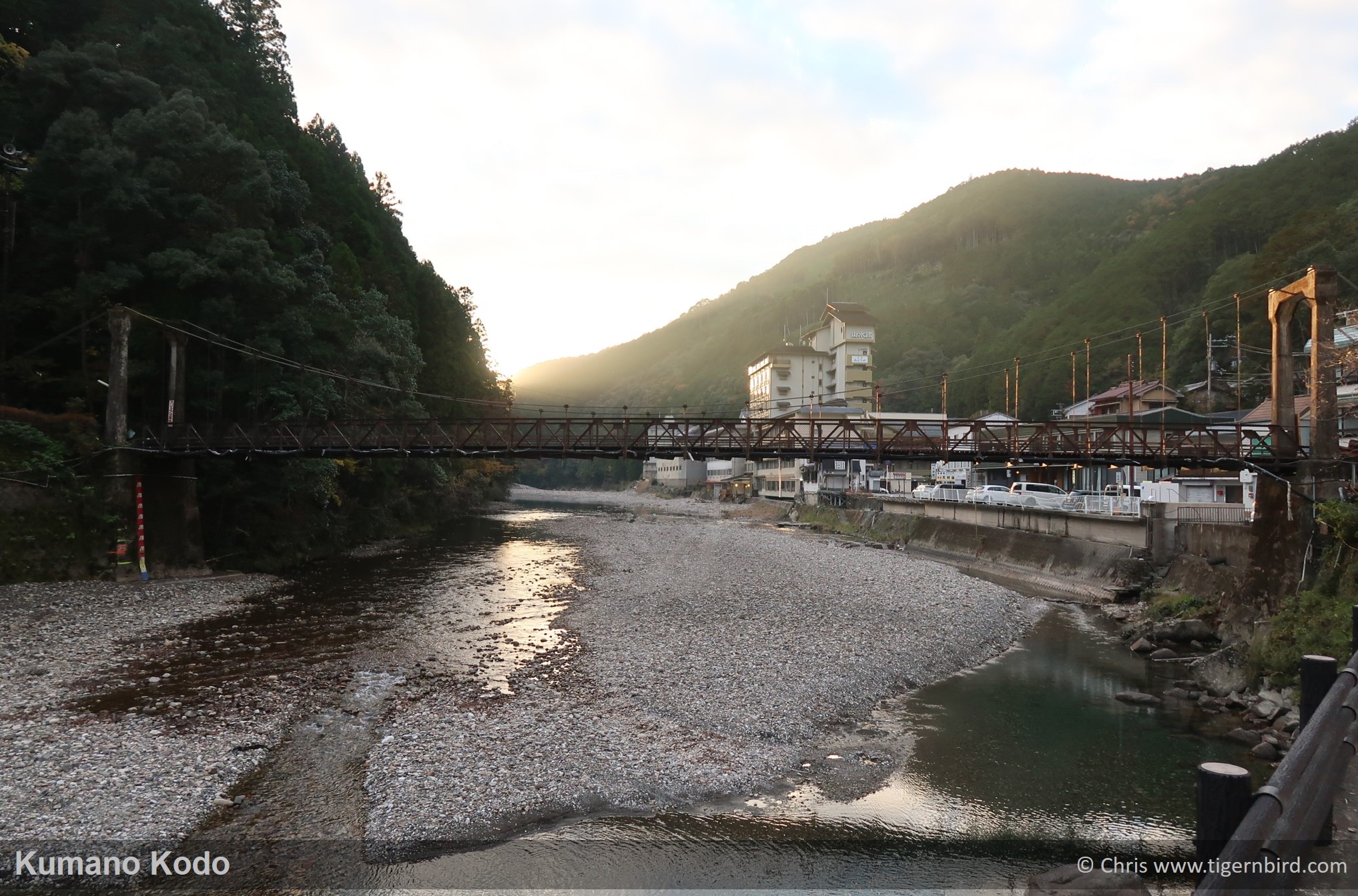 Rusty metal bridge over rocky river at Kawayu onsen in Kumano, Japan