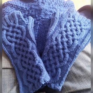 A pair of fingerless mittens with wide cable panels on the backs.