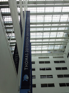 A view of the hospital atrium, a rectangular area of windows with a banner that says "Thomas Jefferson University Hospital."