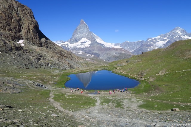 The blue waters of Riffelsee and the Matterhorn gleaming in the clear blue sky.