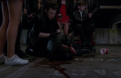 Blaine writhing on the ground in pain as red slushie residue spreads across the ground like blood