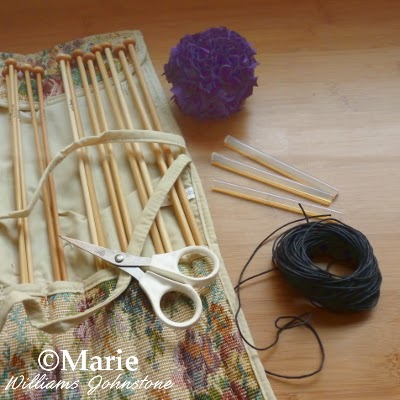 Fabric pom pom, wooden knitting needles, black cord, glue sticks, scissors