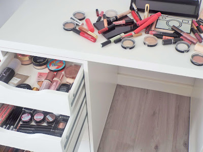 Top shot of base and eye product draws and the larger spread of makeup scattered on top of dressing table, ready for the makeup collection declutter.