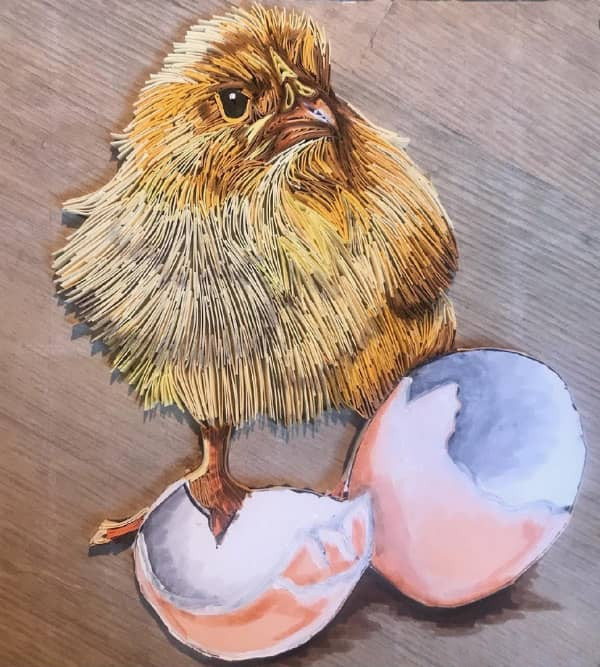 paper quilled portrait of baby chicken standing near pastel painted cracked eggshell