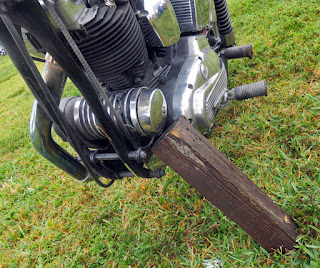 Block of wood serves as kick stand for motorcycle.