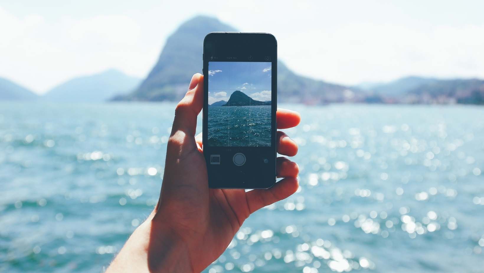 A stock photo from canva of someone taking a photograph of a seascape representing an influencer just sharing the good things in life