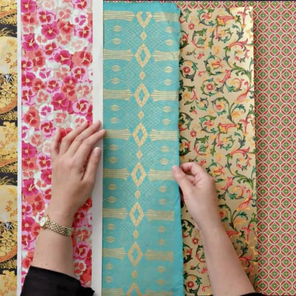 hands handling large sheets of decorative patterned papers