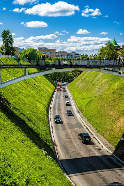 Дорога с машинами среди крутых склонов холмов под пешеходным мостом