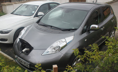 A Nissan Leaf electric car charging outside a solar eco-house.