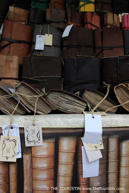 Three rows of handmade notebooks in light brown leather covers with price tags attached that ask for 20 (without stating the exact currency).